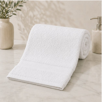 Rolled-up white towel on a marble surface with decorative elements in the background
