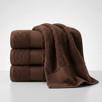 A stack of three folded brown towels with a matching draped towel on top, photographed on a clean light gray studio background.