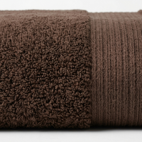 A close-up of a folded brown towel showing two textures: a plush, high-pile terry cloth section on the left and a ribbed knit section on the right, set against a plain white background.