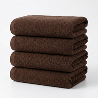 A stack of four folded brown cotton towels on a clean white background.